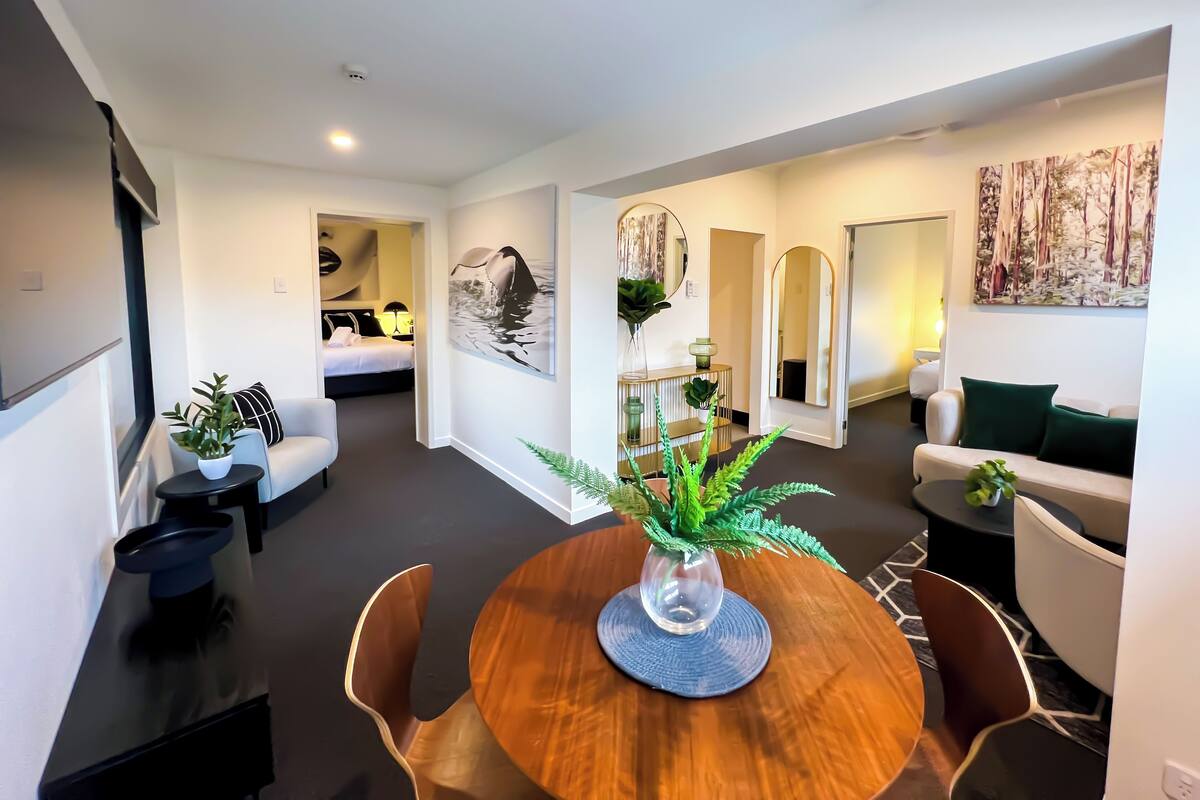 Una habitación de hotel moderna con comedor, sala de estar y dormitorio.