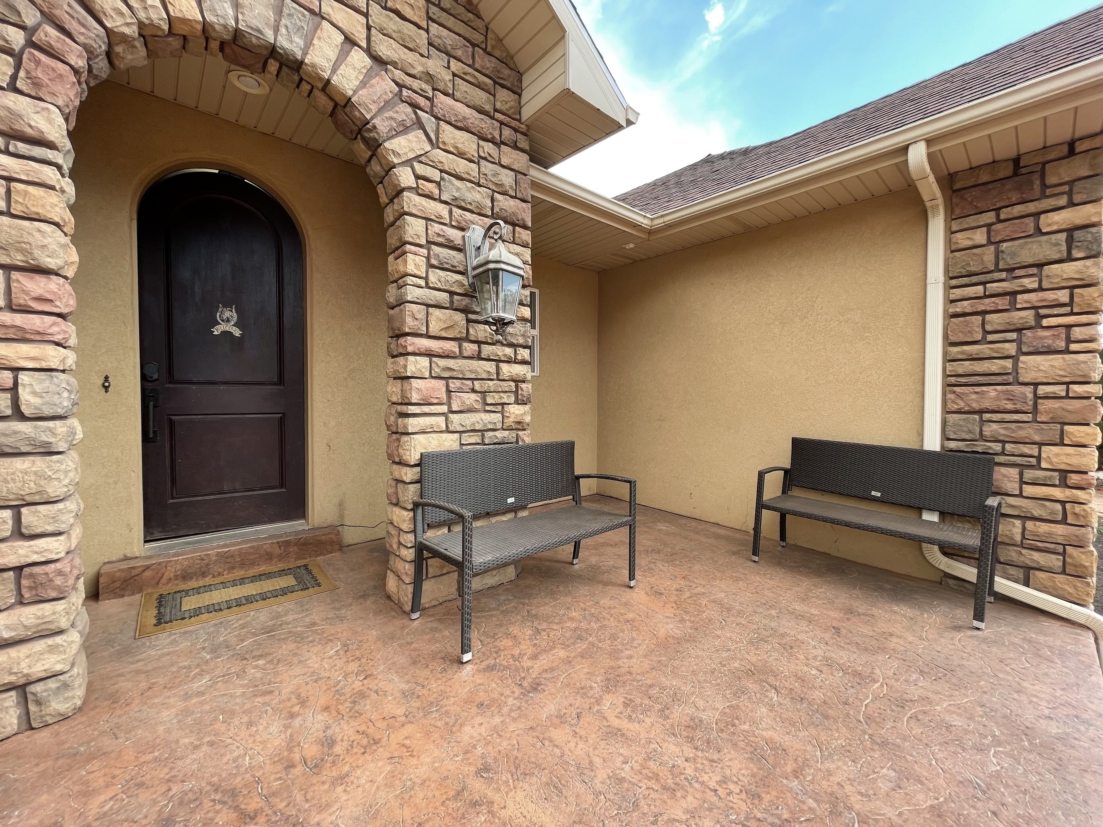 A stone exterior with a dark door and two metal benches.
