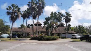 Een hotel met een centrale binnentuin, palmbomen en een gebouw met rieten dak.