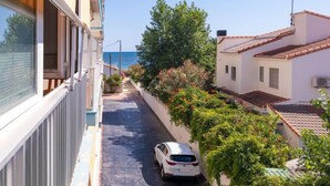 A narrow street flanked by buildings with balconies, a parked car, and a view of the sea. - Hipocampo by Interhome (Dénia)