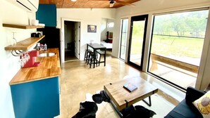 Une cuisine moderne avec un plafond en bois, un îlot central intégré doté d’un évier et un coin repas avec une table et des chaises.