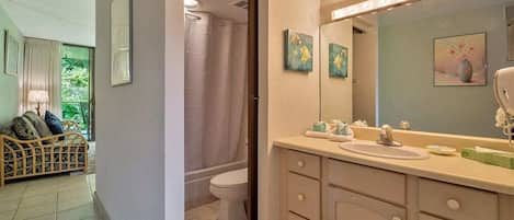 Une salle de bain avec un grand miroir, un lavabo et des toilettes. Il y a un rideau de douche et une fenêtre avec des rideaux.
