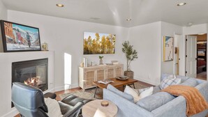A modern living room with a fireplace, a sofa, a coffee table, and a painting on the wall.