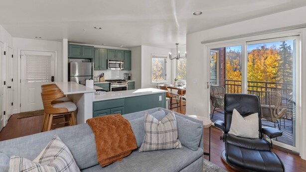 A modern kitchen with teal cabinets, a central island, and a dining area.