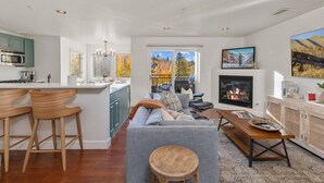 A modern living room with a grey sofa, wooden coffee table, and a fireplace.
