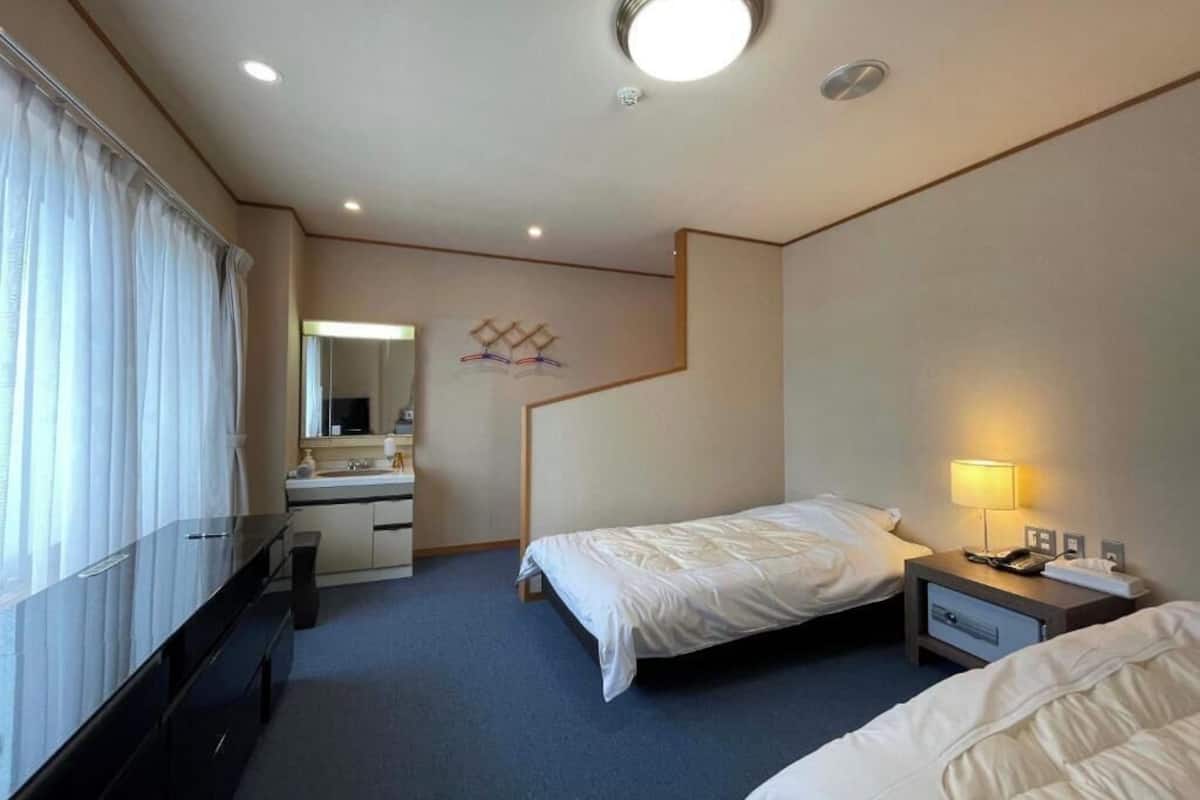 A hotel room with a bed, bedside table, lamp, and a mirror.