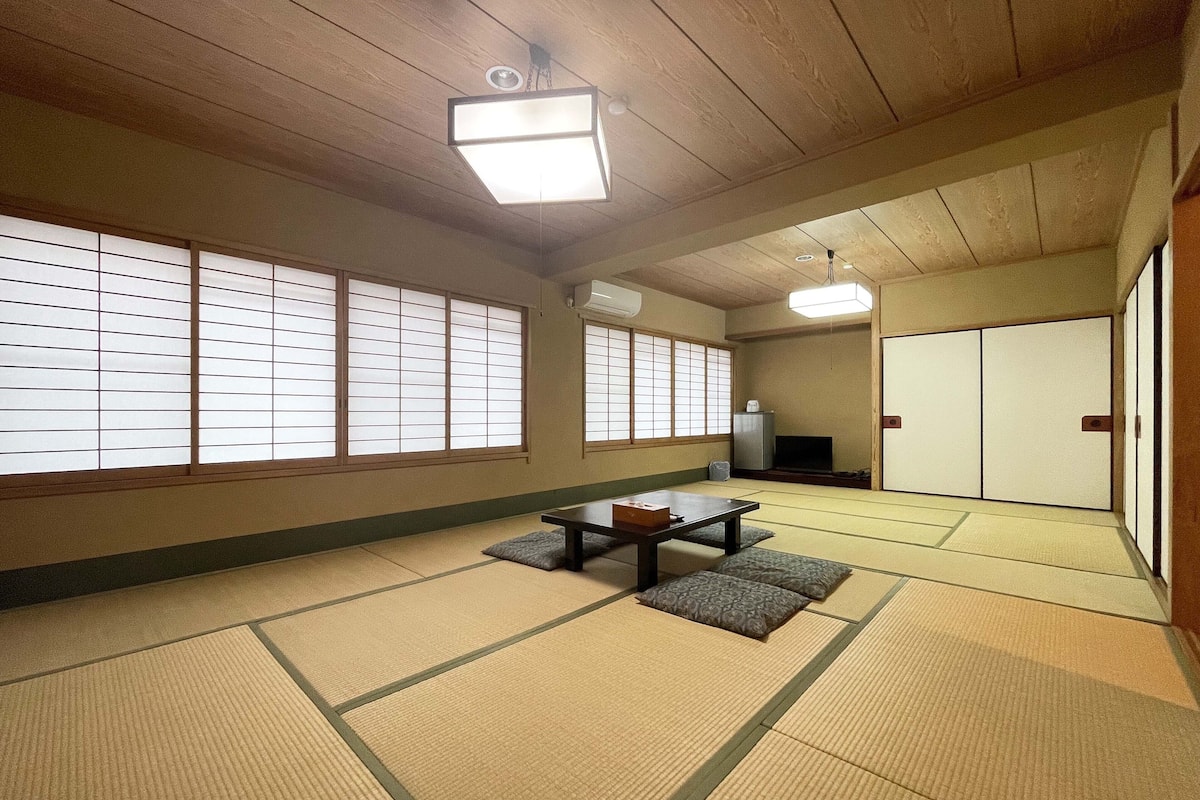 A traditional Japanese room with tatami flooring, sliding doors, and a low table with cushions.