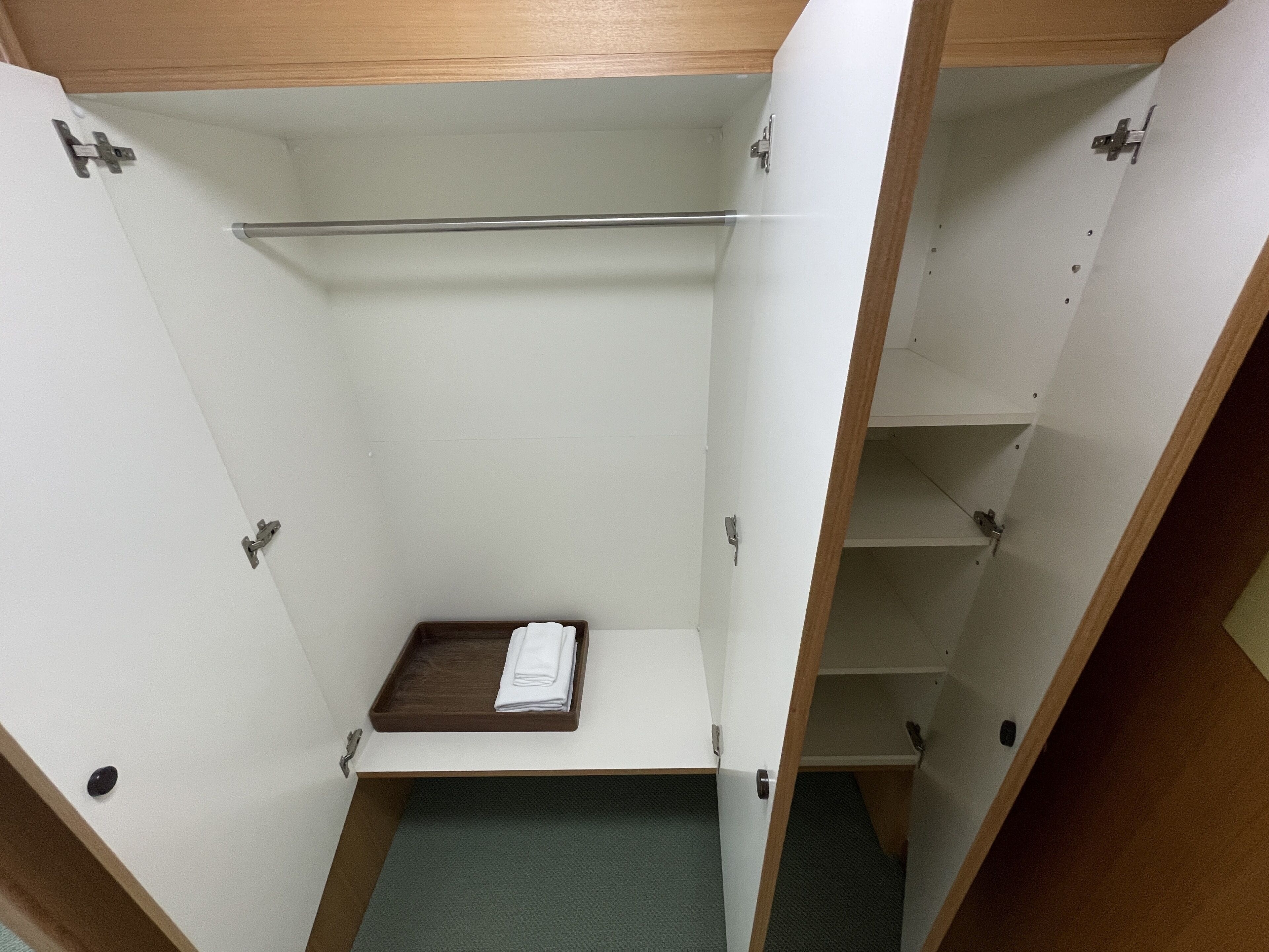 Ein begehbarer Kleiderschrank mit Holzregal, gefaltetem Handtuch und Metallstange.