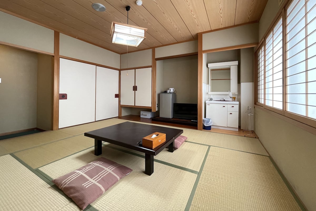 A traditional Japanese room with tatami flooring, a low table, and sliding doors.