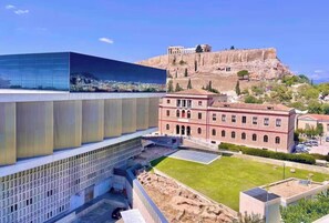 Un edificio moderno con fachada de vidrio, un patio interior y un edificio de estilo clásico al fondo.