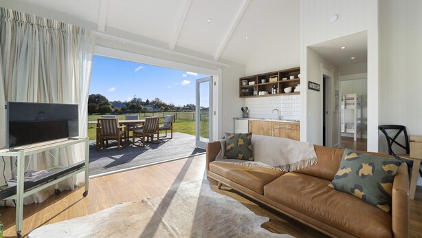 A spacious living area with a TV, sofa, and dining set.