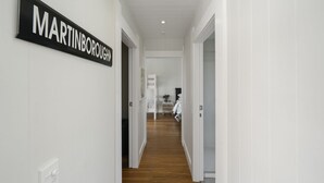 A hallway with a sign reading "MARTINBOROUGH" and a view into a bedroom with a bed and a nightstand.