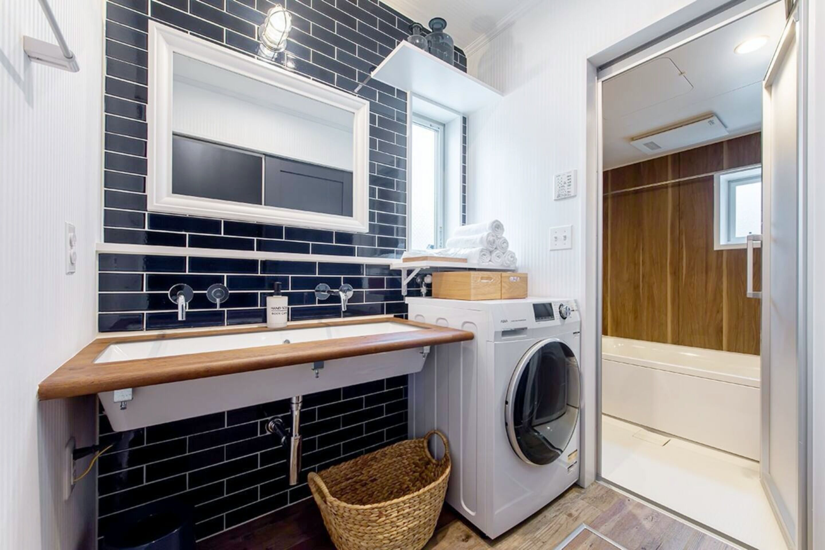 Un espace buanderie compact comprenant un lave-linge, un évier et un étendoir.