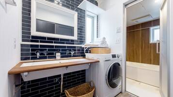 Un espace buanderie compact comprenant un lave-linge, un évier et un étendoir.