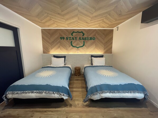 Una habitación con dos camas, techo de madera y una pared con un logo.
