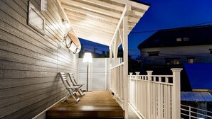 Eine Holzveranda mit weißem Geländer, einer Bank und einer Lampe.