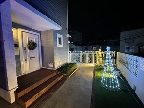 A house with a porch, a door with a wreath, and a fence with lights.