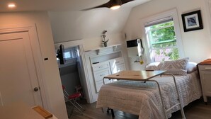 A bedroom with a bed, a ceiling fan, a window with a view, and a desk with a chair. - New Remodeled Studio in Oakland's Dimond District (Oakland)