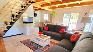 A modern living room with a grey sofa, red cushions, a white coffee table, and a staircase with wooden steps. - 5km from the town center! Cosy villa in a haven of peace (Uzès)