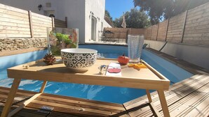A wooden table with a bowl, a glass, and a pumpkin by a pool. - 5km from the town center! Cosy villa in a haven of peace (Uzès)