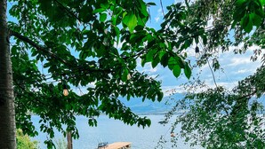 A lakeside deck with a wooden bench and a small garden area with rocks and plants. - Private Lakefront Beach House off Naramata Bench with sauna and hot tub (Penticton)