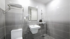 Un baño moderno con lavamanos blanco, espejo, toallero y ducha.