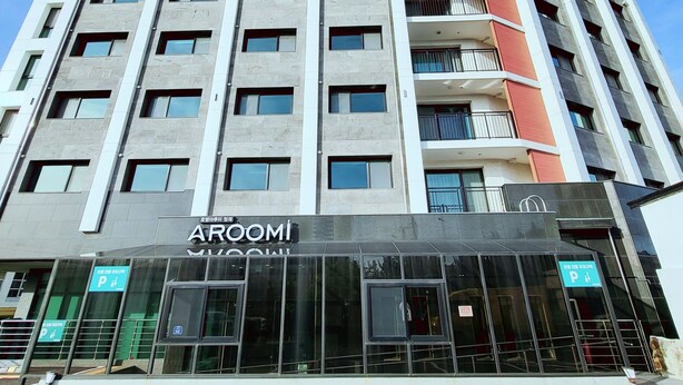Un hotel de varios pisos con una fachada moderna, que presenta un llamativo letrero de 'ARQOMI' a nivel de calle.