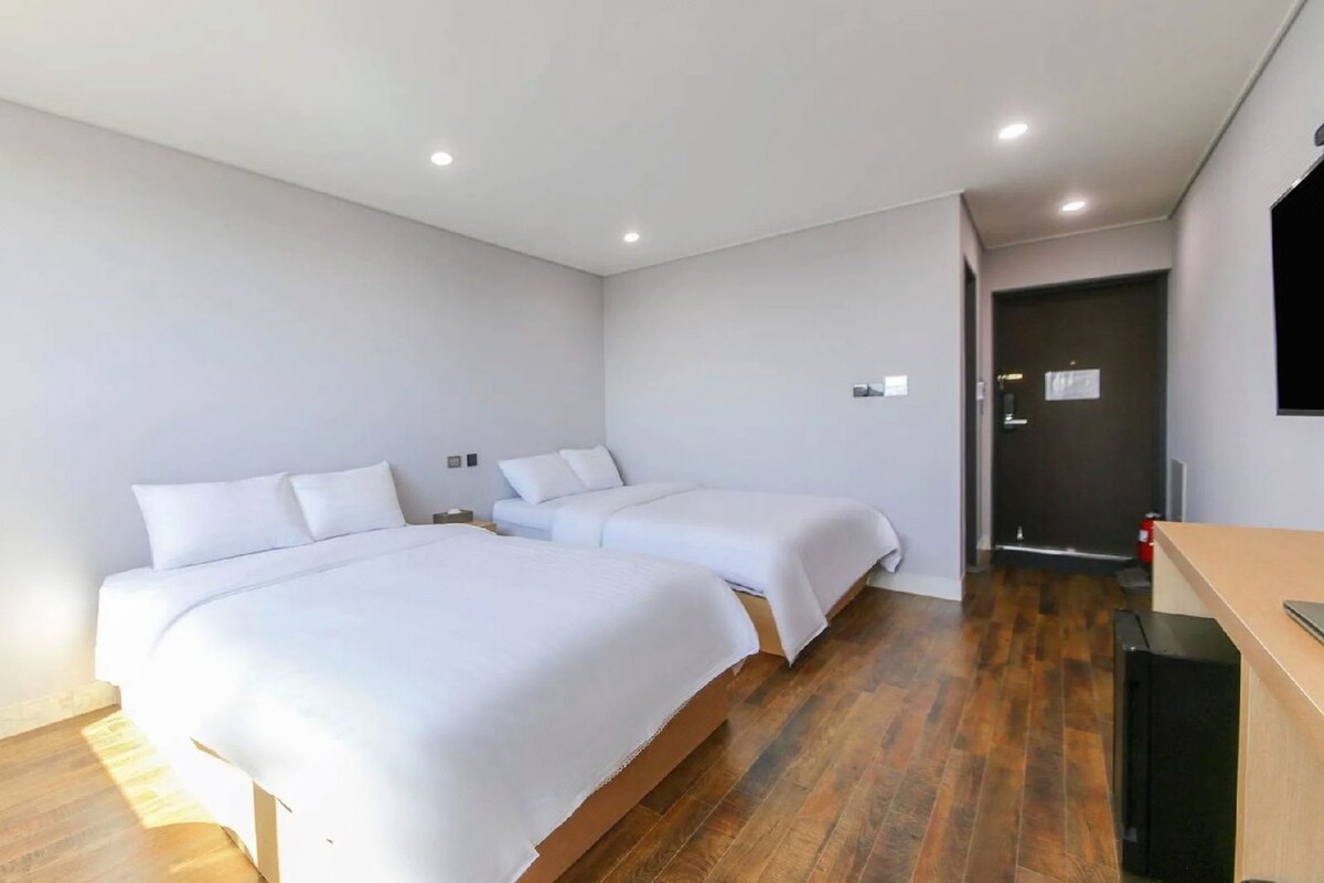 Una habitación de hotel con dos camas, un escritorio y una silla.
