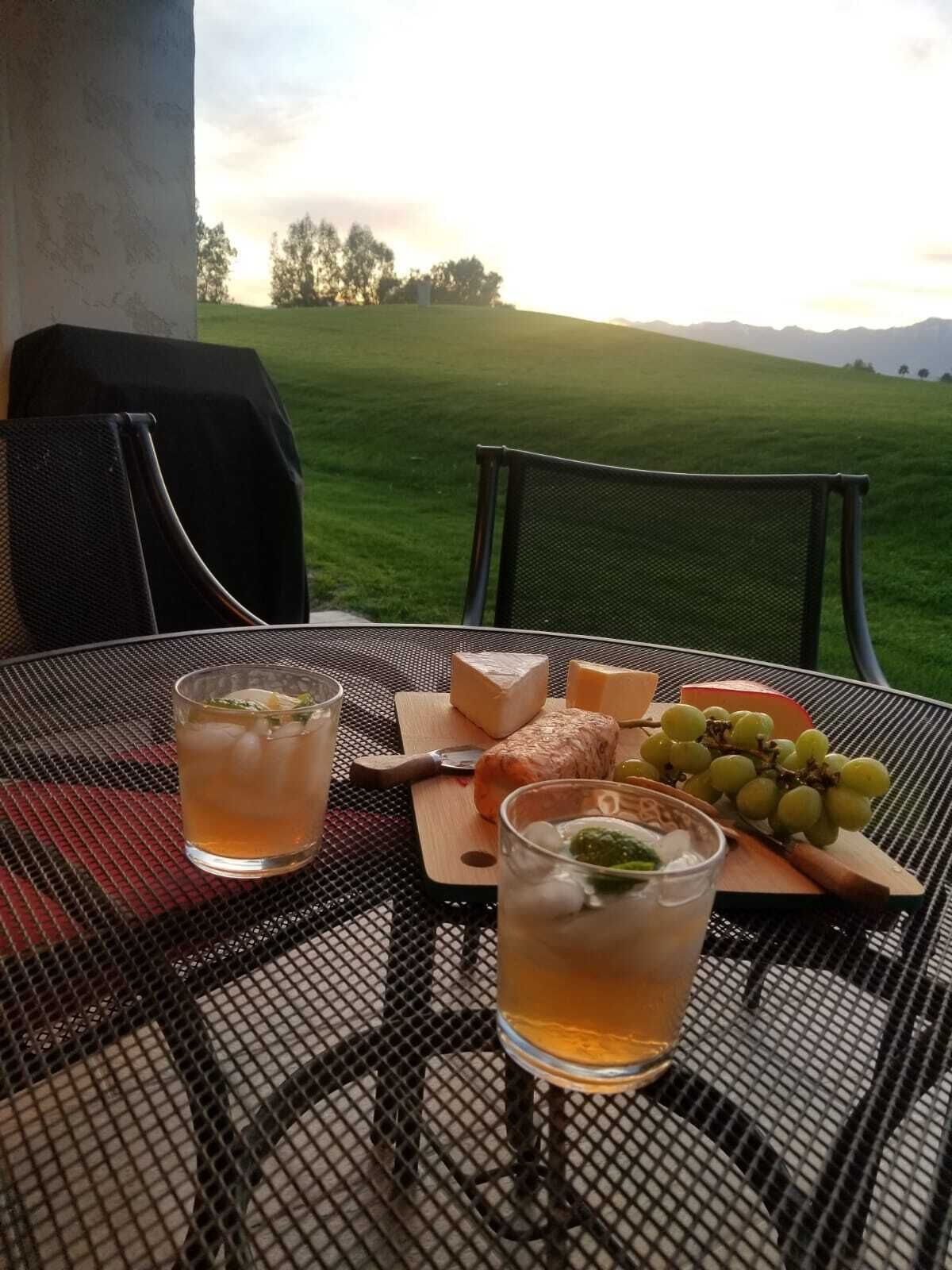 A table set outdoors with a view of a grassy field and mountains.