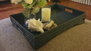 A room with a black woven tray on a carpet, containing a vase with white flowers, a candle, and decorative items. - Desert Falls Country Club (Palm Desert)