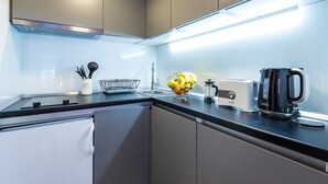 A modern kitchen with a black countertop, stainless steel appliances, and a fruit bowl. - Apartment Kantun (Dubrovnik)