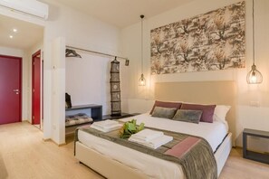 A bedroom with a bed, a wall-mounted artwork, a hanging light fixture, and a bedside table. - Velluto Blu (Verona)