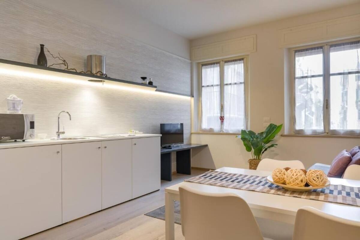 A modern kitchen with white cabinets, a built-in microwave, and a flat-screen TV.