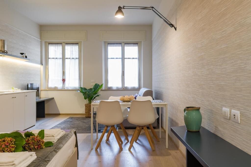A modern kitchen with white cabinets, a dining area with two chairs, a table, and a vase on a counter.