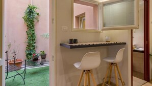 A compact kitchen with a built-in window, a small bar area with stools, and a potted plant. - Velluto Blu (Verona)