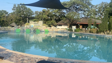 Una piscina al aire libre, camas de piscina con cargo, sombrillas