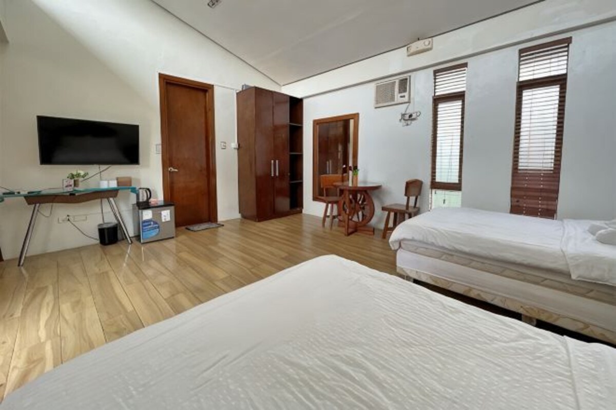 Une chambre avec deux lits, un bureau, une télévision et une armoire.