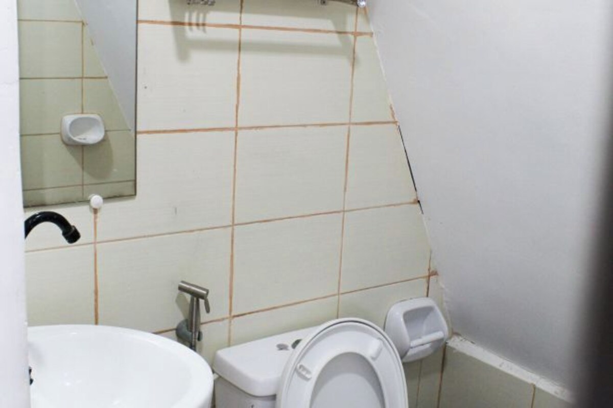 Une salle de bain avec un lavabo blanc, des toilettes et un miroir.