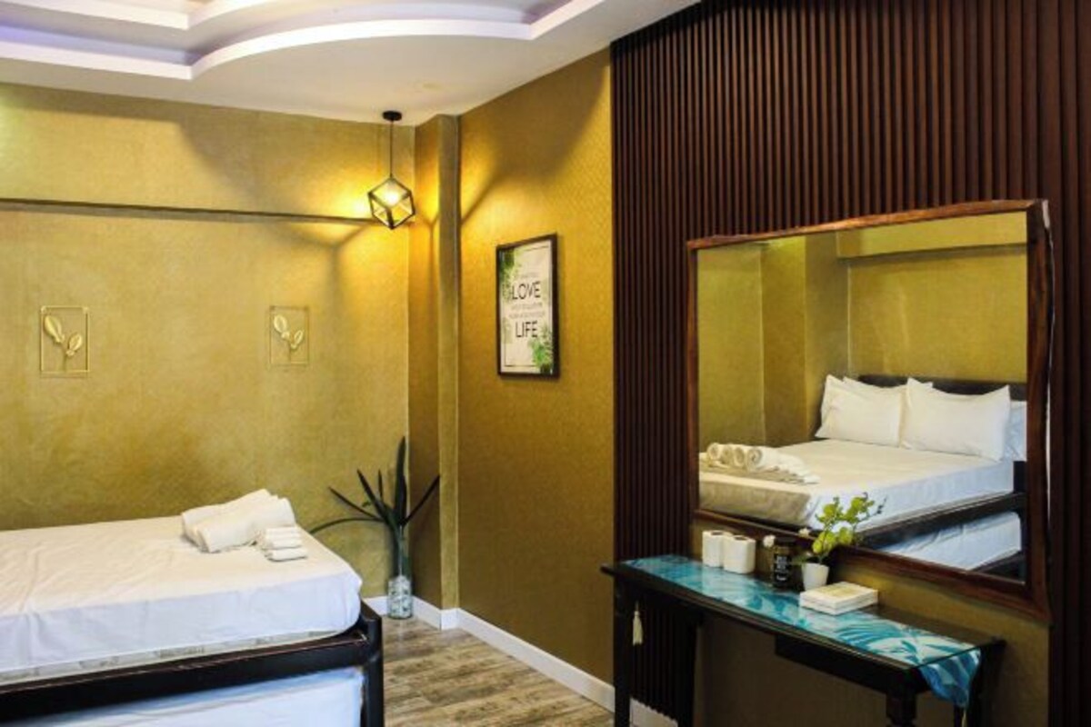 Une chambre d’hôtel équipée d’un lit, d’une table de chevet, d’un miroir et d’un luminaire fixé au mur.