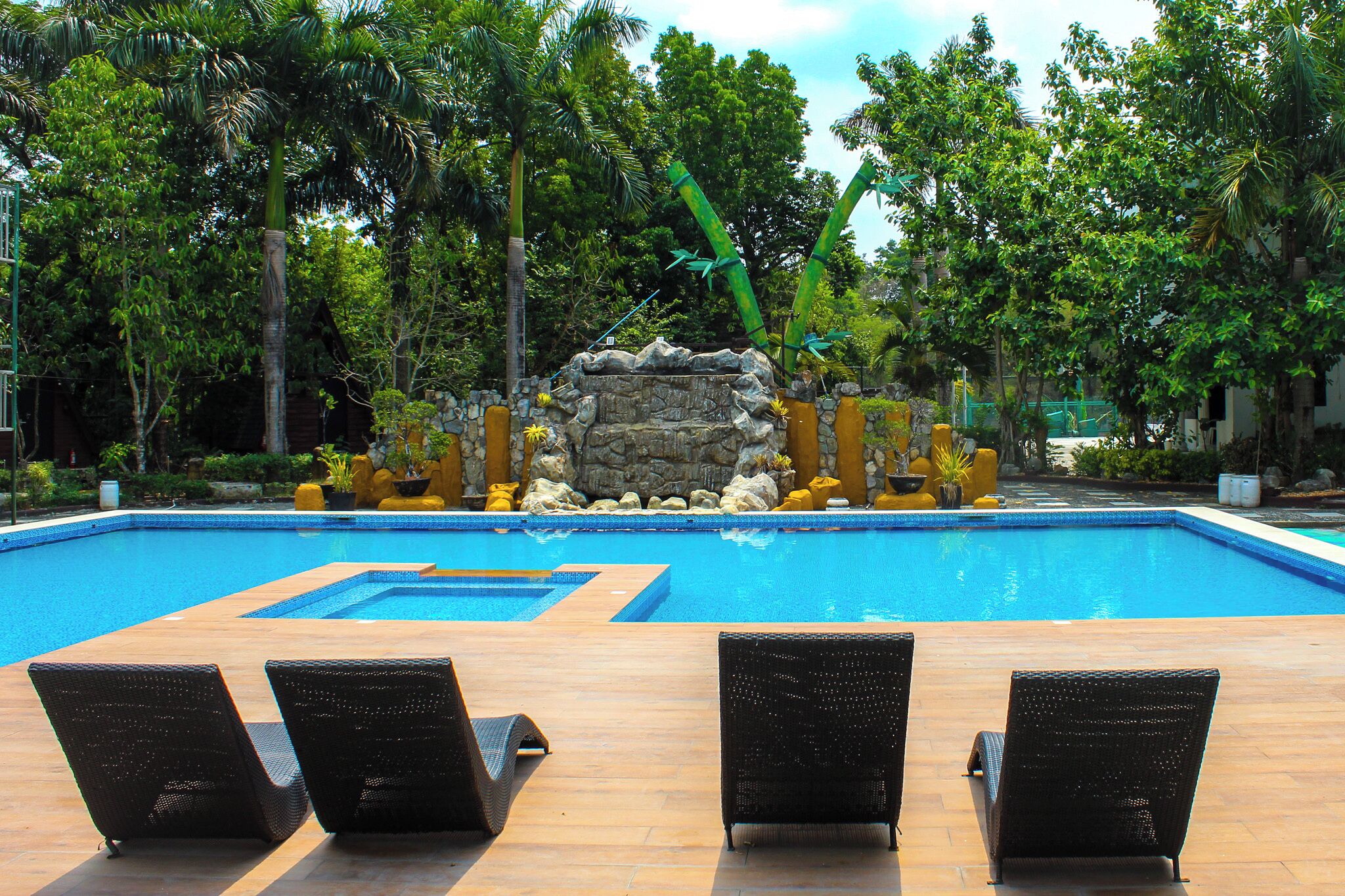 A swimming pool with lounge chairs and a rock feature.