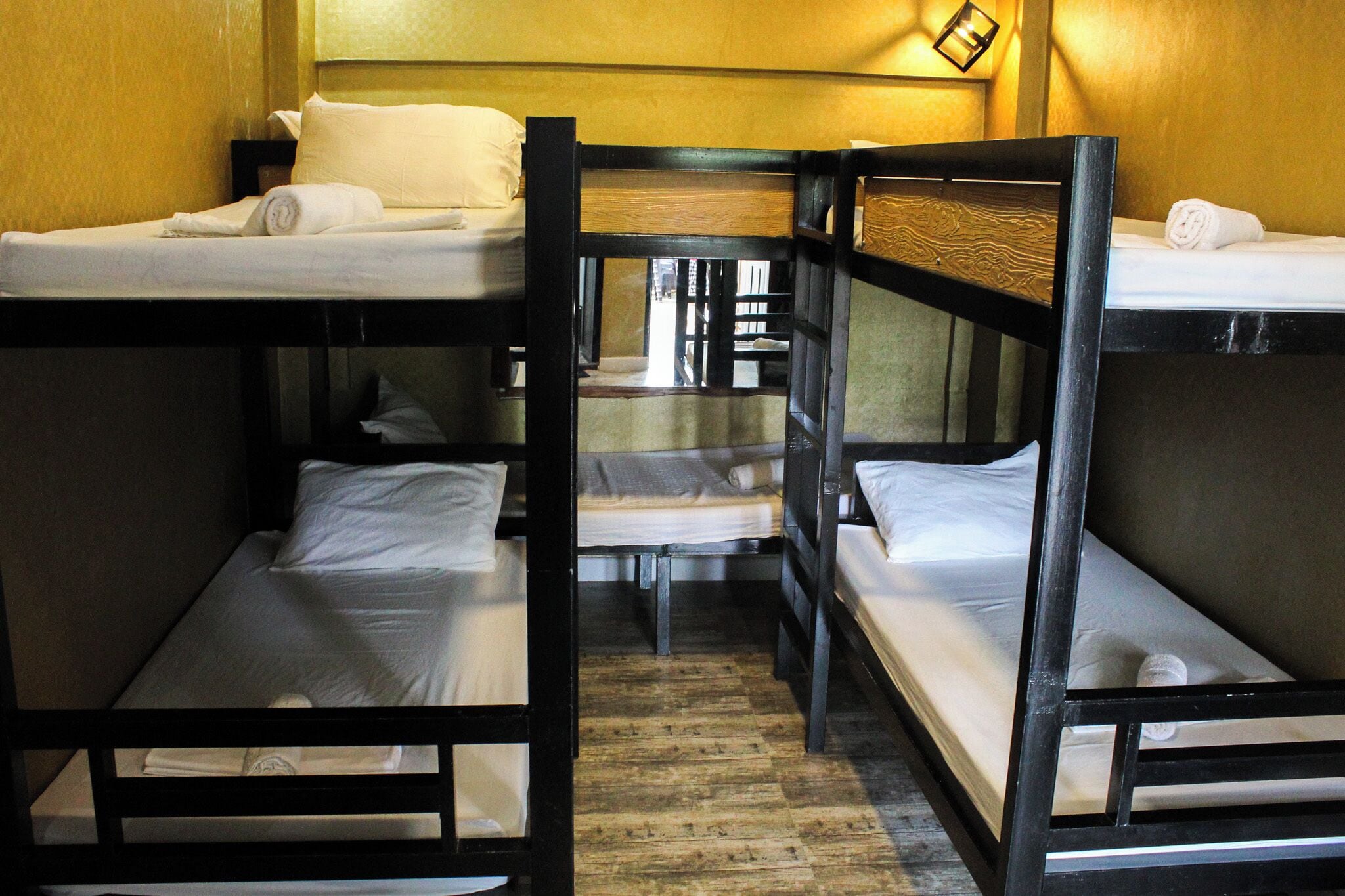 Une chambre avec un lit superposé, dont la structure est en bois et la literie est blanche.