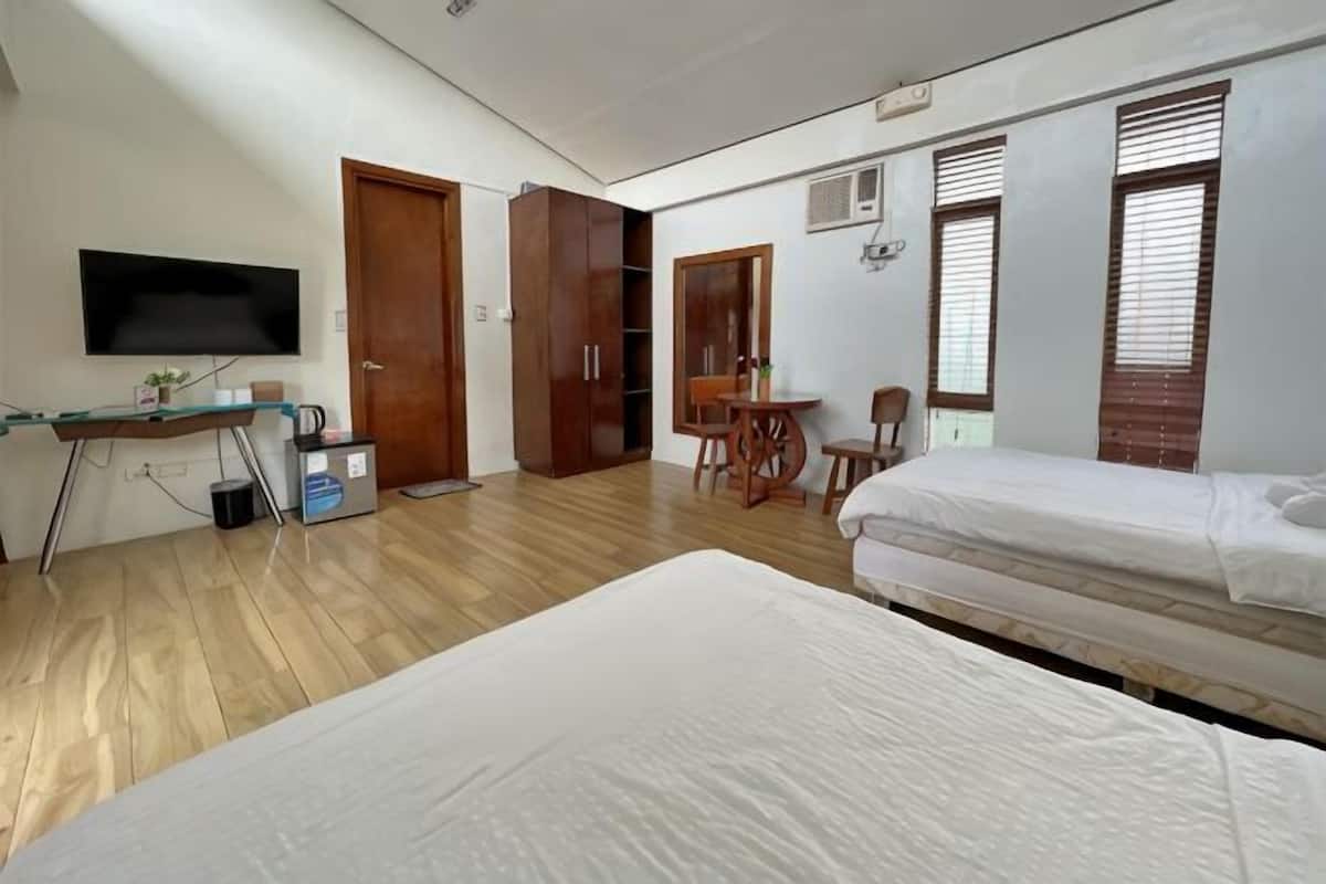 Une chambre avec deux lits, un bureau, une télévision et une armoire.