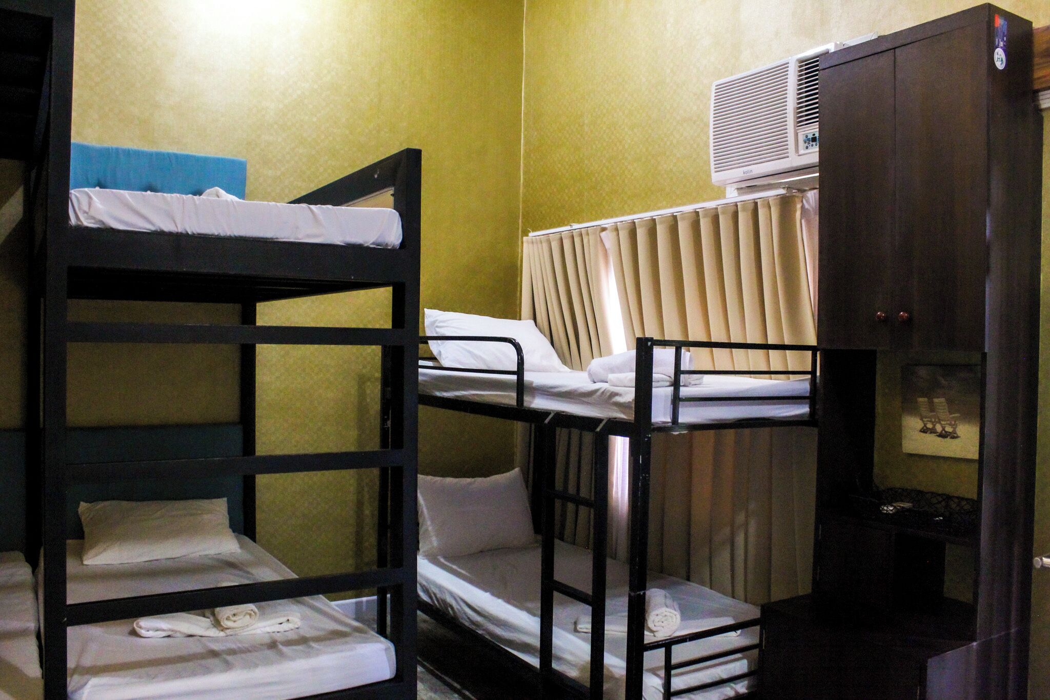 Dormitorio con literas, ventana, calentador y una mesita.