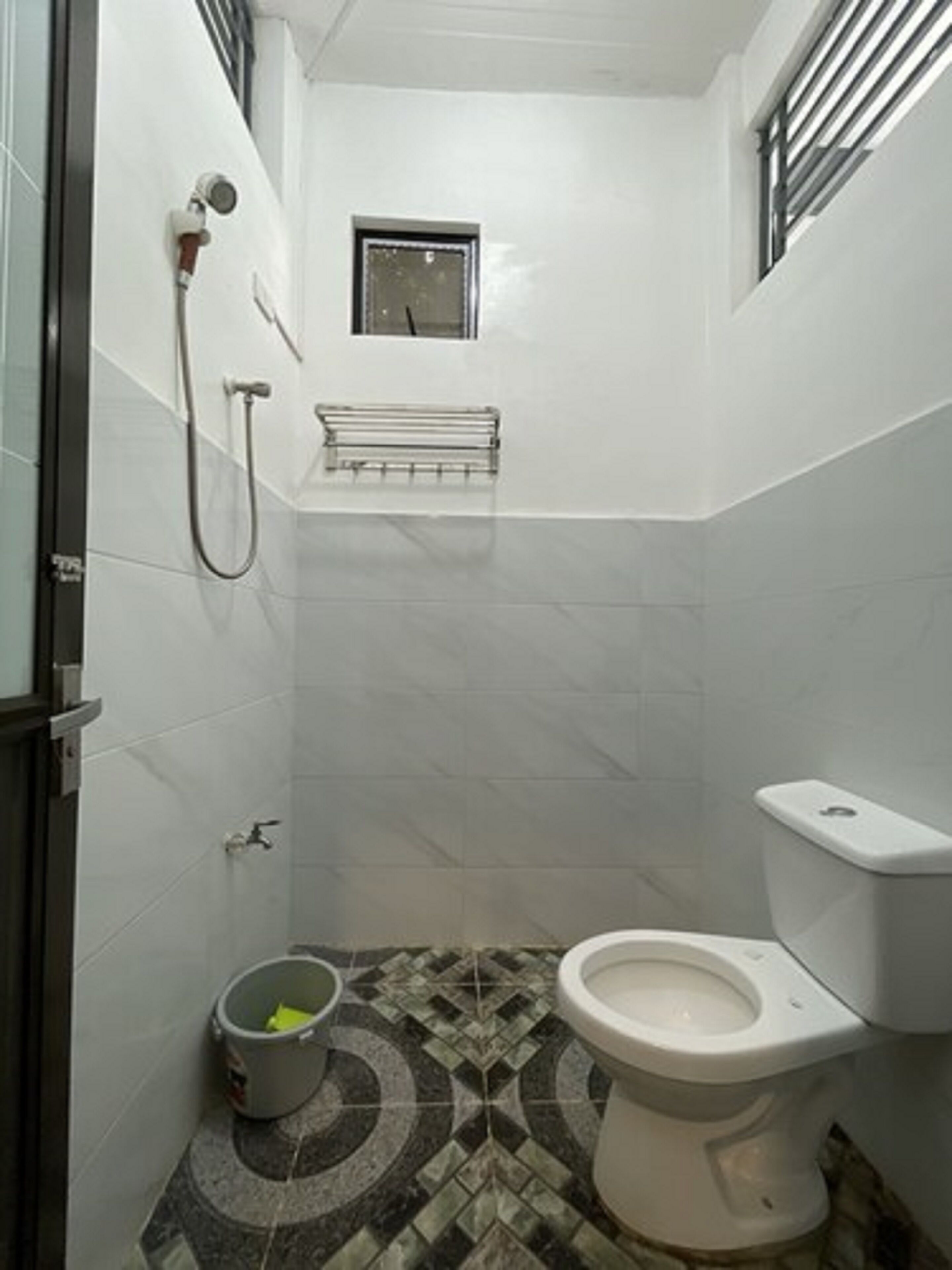A small, compact bathroom with a toilet, a shower, and a small window.