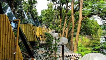 Ein bewaldetes Gebiet mit einer Seilbrücke, Bambuskonstruktionen und einem kugelförmigen Laternenpfosten.