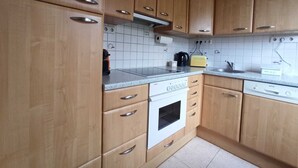 Keittiössä on puukuvioiset kaapit, valkoinen liesi, leivänpaahdin ja pesuallas.