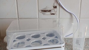 Kannettava vedenpuhdistin, jossa on läpinäkyvä säiliö ja mitta-asteikot, on sijoitettu kuvioituun työtasoon.