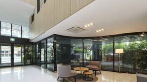 A modern lobby with a glass wall, a round table, and two chairs. - Jeju Grace Hotel (Seogwipo)