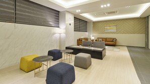 A modern lounge area with seating, a coffee table, and a lamp. - Jeju Grace Hotel (Seogwipo)