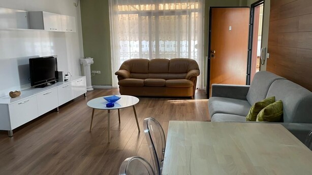A living room with a sofa, a dining table, and a TV on a cabinet. - Great value for its price (Tirana)